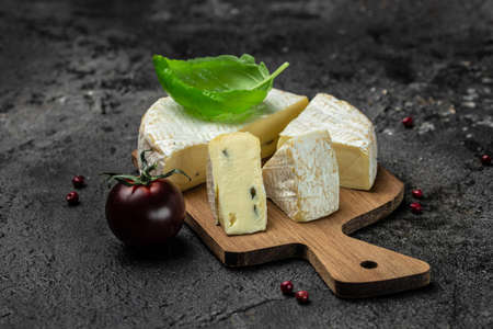 Brie cheese with a white and blue mold, camembert cheese. truffled brie cheese on a dark background,...