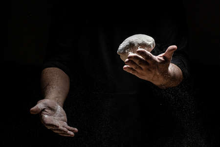 Beautiful and strong men's hands knead the dough from which they will then make bread, pasta or...