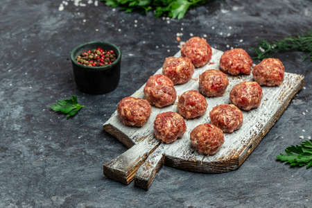 raw meatballs on wooden board, minced pork meat with spices on a dark background. Food recipe background. close up.の写真素材