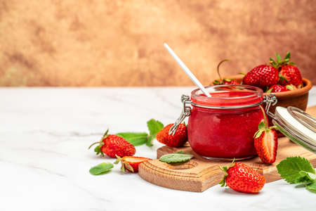Jar of strawberry jam and fresh berries on wooden board white background. Long banner format.の写真素材