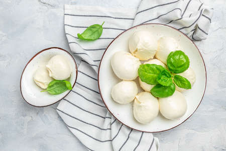 Cheese collection, white balls of soft Italian cheese mozzarella, served with fresh basil leaves on...