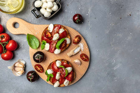 Open sandwiches with cherry tomatoes, mini mozzarella, fresh basil leaves, caprese on bread, Traditional italian appetizer or snack, antipasto. banner, menu, recipe place for text, top view.の写真素材