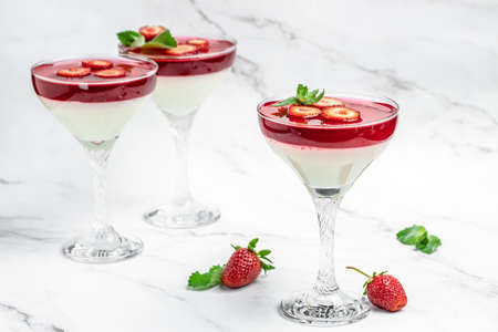 Italian panna cotta dessert with strawberry and mint on a light background. Summer yogurt dessert....