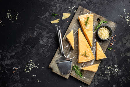 Parmesan cheese on a wooden board, Hard cheese, olives, rosemary and metal grater. place for text, top view.の写真素材