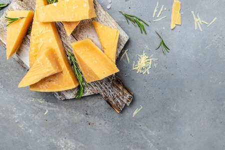 Sliced and grated parmesan cheese with rosemary on a gray table, banner, menu, recipe place for...
