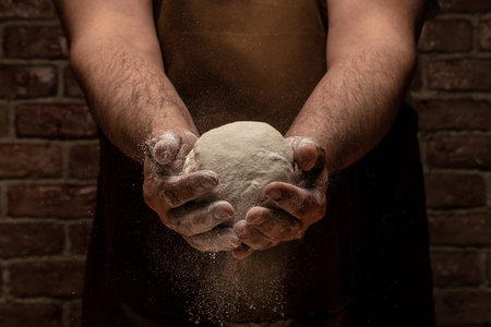 White flour flying into the air as pastry chef in white suit slams ball dough on white powder covered table. concept of nature, Italy, food, diet and bio.の写真素材