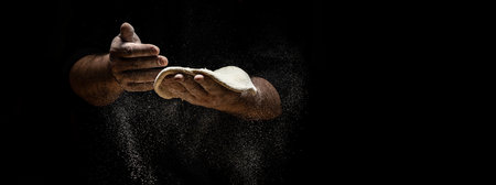 Clap hands of baker with flour. Beautiful and strong men's hands knead the dough make bread, pasta or pizza. Powdery flour flying into the air. Long banner format.の写真素材
