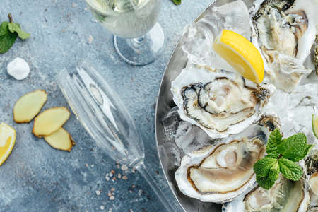many kinds opened oysters in a plate with ice and lemon on blue background, Healthy food, gourmet food. Oyster dinner in a restaurant. top view,の写真素材