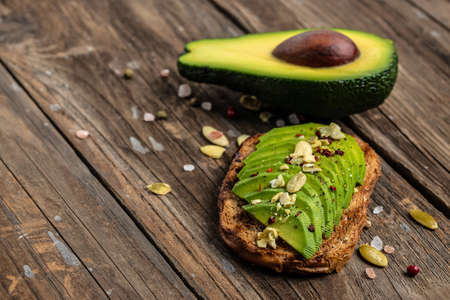 Avocado sandwich on dark rye bread pumpkin seeds, salt and pepper. Vegetarian food. plant-based...