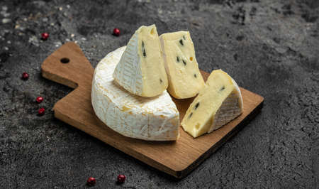 Brie cheese with a white and blue mold, camembert cheese. truffled brie cheese on a dark background,...