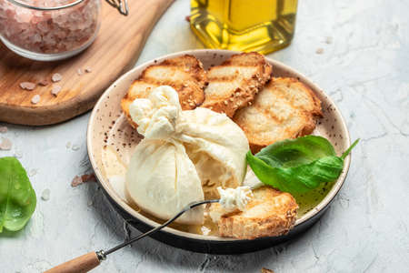 Italian burrata cheese, white balls of burrata or burratina cheese Basil and Olive Oil and Ciabatta. place for text, top view.の写真素材