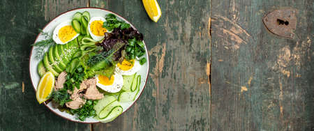 Healthy nutritious paleo keto breakfast diet tuna, avocado, egg, cucumber and fresh salad. Keto breakfast or lunch. Long banner format. top view.の写真素材