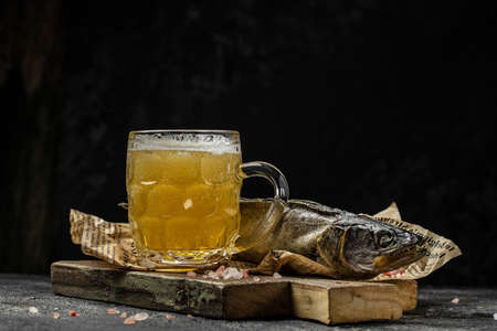 Foam beer in a mug, dried fish stockfish dark background. Beer brewery concept. place for text.