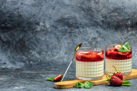 Dessert Panna Cotta with fresh strawberry in glass with strawberries. Italian dessert on a blue background. Restaurant menu, dieting, cookbook recipe top view.の写真素材
