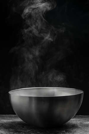 Steaming pot on black background, Hot food concept. Bowl of hot steam of hot soup with smoke,の写真素材