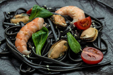 Pasta black spaghetti with prawn and mussels seafood. on dark background. Black spaghetti. banner, menu, recipe place for text, top view.の写真素材