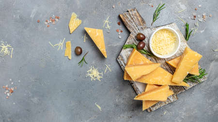 Sliced and grated parmesan cheese with rosemary on a gray table, banner, menu, recipe place for text, top view.の写真素材