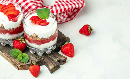 strawberry parfaits with fresh fruit, yogurt and granola on white table, glass jar. Healthy breakfast. Long banner format. top view.の写真素材