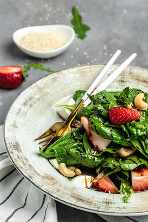 Fresh vegetarian salad with kale, strawberry, spinach leaves and feta cheese. vertical image. top view,の写真素材