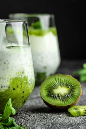 Healthy breakfast chia pudding with kiwi in glass jars on a white table. Clean eating, dieting, vegan food concept. vertical image.の写真素材