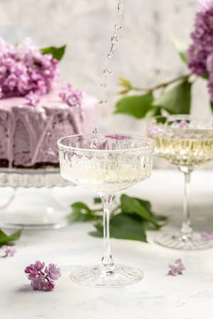 Delicious prosecco, champagne, wine with berry mousse cake bouquet of purple blooming lilacs, French cuisine, postcard, background.の写真素材