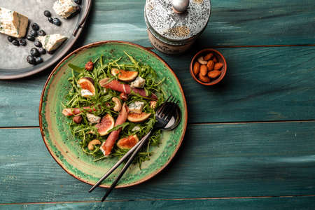 Delicious gourmet cheese, assortment of soft cheeses served with sliced sweet fresh figs and grapes on a rustic wooden background, catering, banner, menu, recipe, place for text.の写真素材