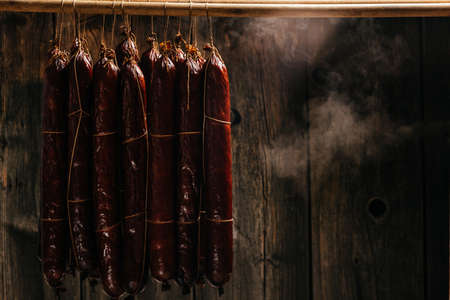 The process of smoking hanging sausages in the smokehouse. Clouds of smoke rise up and envelop the sausages hanging in a row. long banner format,の写真素材