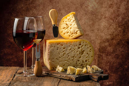 cheese and wine on a wooden background. maasdam or Emmental with big holes. place for text.の写真素材