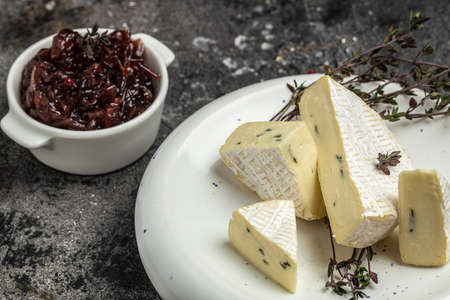 Brie cheese with a white and blue mold, camembert cheese on a wooden board. truffled brie cheese on...