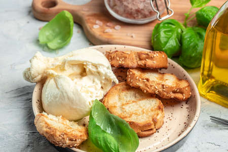 fresh handmade soft Italian cheese from Puglia, white balls of burrata or burratina cheese Basil and Olive Oil and Ciabatta. place for text, top view.の写真素材