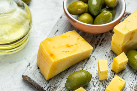 Homemade hard cheese with olives on old wooden board light background. banner, menu, recipe place for text, top view.の写真素材