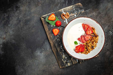 Granola with yogurt with fresh strawberry, chia seeds and honey on a gray background. Delicious balanced food concept. banner, menu, recipe place for text, top view.の写真素材