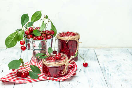 cherry jam in a jar and fresh berries on the table. Preserved organic food from garden on a light background. banner, menu, recipe place for text.の写真素材