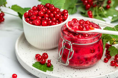red currant jam with fresh berries. Canned berries on a light background. Food recipe background. close up.の写真素材