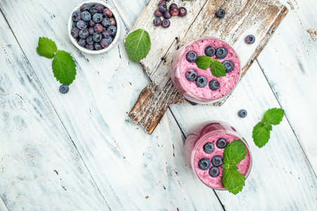 yogurt and blueberries milkshake or yogurt. Fresh raw organic berry drink in glasses on a light background. banner, menu, recipe place for text, top view.の写真素材