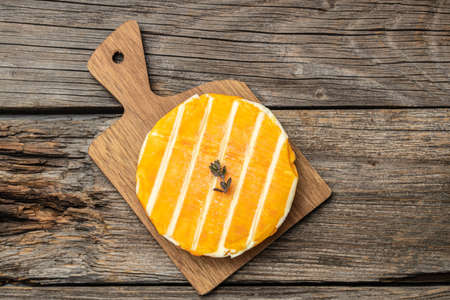 cream Round brie or Camembert cheese on a wooden board. Rougette cheese on a wooden background,...