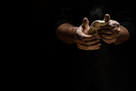 hands knead the dough from which they will then make bread, pasta or pizza. A cloud of flour flies...