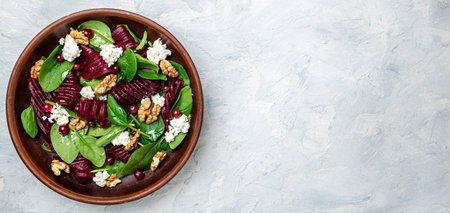 Healthy Beet Salad with fresh sweet baby spinach, cheese, nuts, cranberries. Clean eating, dieting, vegan food concept. Long banner format. top view.の写真素材
