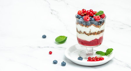 yogurt granola parfait with blueberry and raspberry on a light background. Long banner format.の写真素材