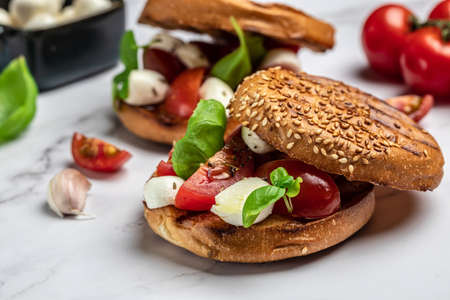 Open sandwiches with cherry tomatoes, mini mozzarella, fresh basil leaves, caprese on bread, Traditional italian appetizer or snack, antipasto. banner, menu, recipe place for text, top view.の写真素材