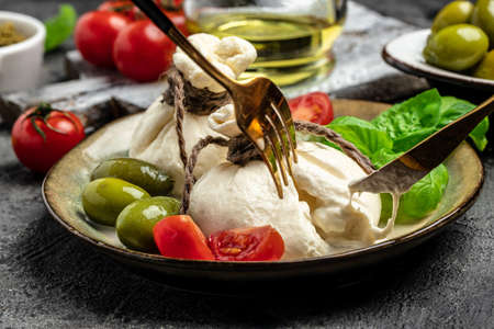 Antipasto burrata cheese salad served with cherry tomatoes, fresh basil leaves, prosciutto ham and olives. prosciutto, mozzarella. vertical image. top view. place for text.の写真素材