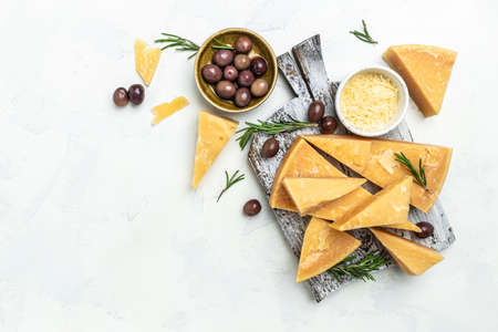 Pieces of parmigiano reggiano or parmesan cheese. Sliced and grated parmesan cheese with rosemary on a light table, Long banner format. top view.の写真素材