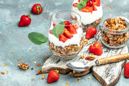 Parfait Greek yogurt with fresh strawberry and granola on a wooden board. gluten free diet, healthy breakfast. banner, menu, recipe place for text, top view,の写真素材