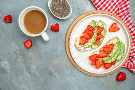 toasts or bruschetta with strawberry, avocado, soft cheese and chia seeds on a blue background. healthy breakfast or lunch. Keto diet. place for text, top view.の写真素材