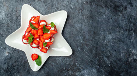 Tiramisu. Homemade tiramisu cake with fresh strawberry, mascarpone and mint. Tiramisu portion on plate on dark background. Delicious no bake tiramisu.の写真素材