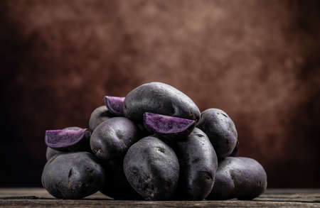 Raw sweet potatoes on wooden background, Organic purple sweet potatoes. Raw sweet potatoes or batatas. pomoea batatas. Batata potato, banner, menu, recipe place for text,の写真素材