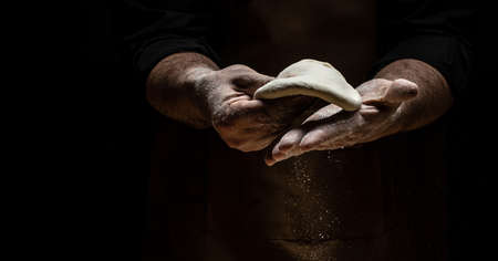 flying pizza dough with flour scattering in a freeze motion of a cloud of flour midair on black....