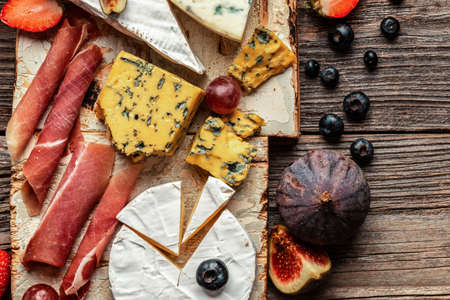 Various kind of cheese with grapes and figs on a wooden background,の写真素材