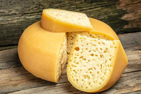 close up french hard cheese with holes emmentaler on a wooden background. farmer market. place for...