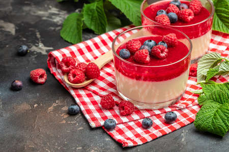 Raspberry Panna cotta with raspberry jelly on a dark background. Berry dessert with cream sauce in small jars. place for text.の写真素材